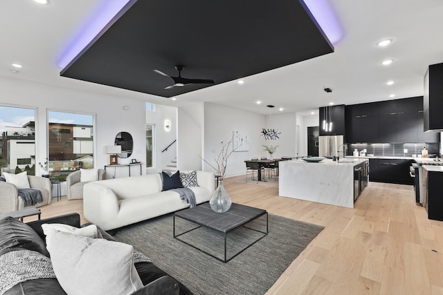 living room with ceiling fan, sink, and light hardwood / wood-style floors