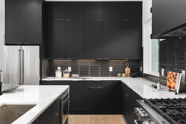 kitchen featuring backsplash, high quality fridge, oven, range, and light hardwood / wood-style flooring