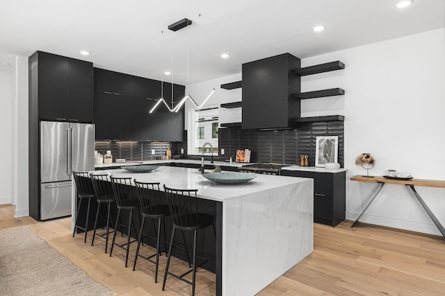 kitchen featuring pendant lighting, high end fridge, and an island with sink