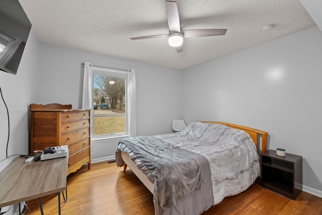 bedroom with hardwood / wood-style flooring, ceiling fan, and a textured ceiling