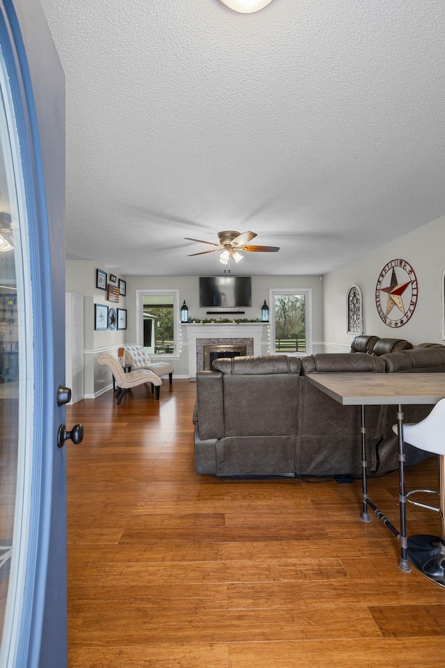 living room featuring wood-type flooring, a textured ceiling, and ceiling fan