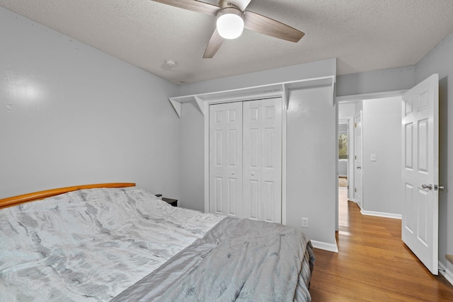 bedroom featuring a textured ceiling, a closet, ceiling fan, and light hardwood / wood-style floors