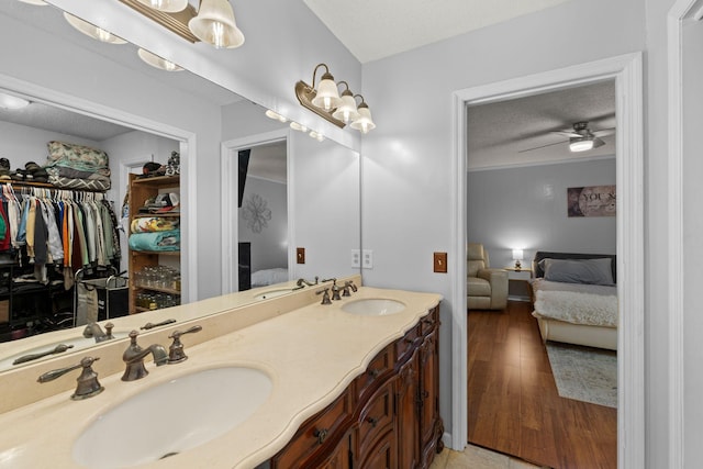 bathroom featuring ceiling fan, vanity, wood-type flooring, and a textured ceiling