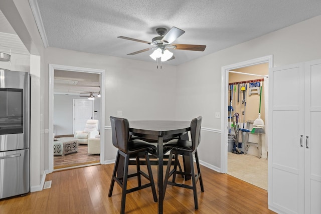 dining room with ceiling fan, a textured ceiling, and light wood-type flooring