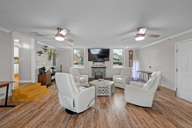 living room with a fireplace, hardwood / wood-style flooring, ceiling fan, and ornamental molding