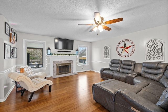 living room featuring a healthy amount of sunlight, ceiling fan, wood-type flooring, and a textured ceiling