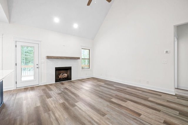 unfurnished living room featuring hardwood / wood-style flooring, ceiling fan, and high vaulted ceiling