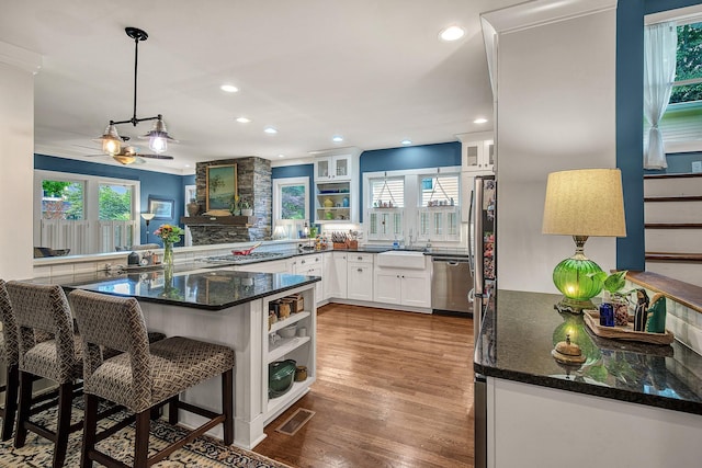 kitchen with kitchen peninsula, crown molding, white cabinetry, hanging light fixtures, and a breakfast bar area