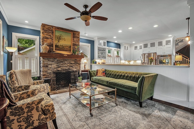 living room featuring ceiling fan, sink, a stone fireplace, and hardwood / wood-style floors