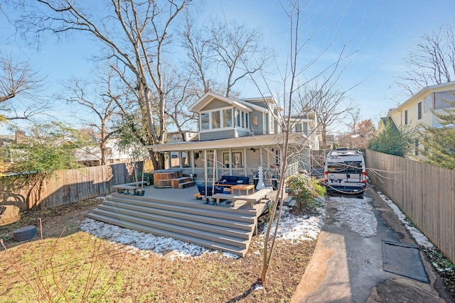 back of property with a hot tub and a wooden deck