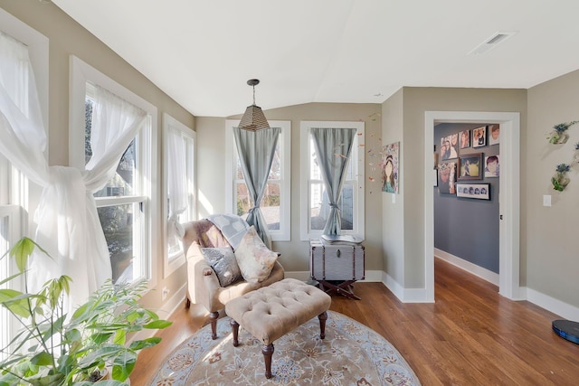 living area with vaulted ceiling, a wealth of natural light, and wood-type flooring