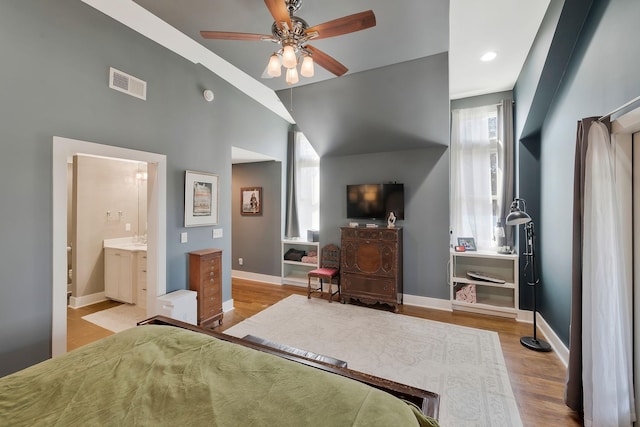 bedroom featuring ceiling fan, ensuite bathroom, lofted ceiling, and light hardwood / wood-style flooring