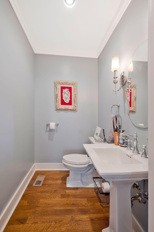 bathroom with hardwood / wood-style flooring, toilet, and ornamental molding