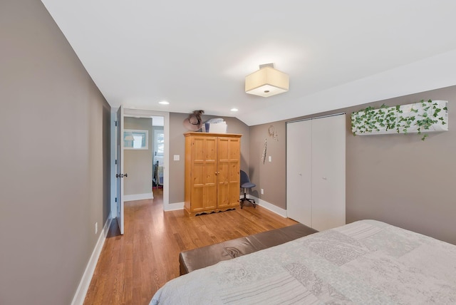 bedroom featuring wood-type flooring, a closet, and lofted ceiling