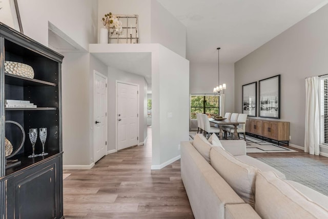 living room featuring a towering ceiling, wood-type flooring, and an inviting chandelier