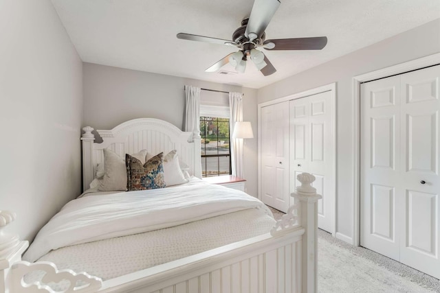 bedroom featuring ceiling fan, light colored carpet, and two closets