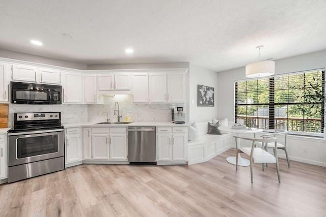 kitchen with white cabinets, stainless steel appliances, hanging light fixtures, and sink