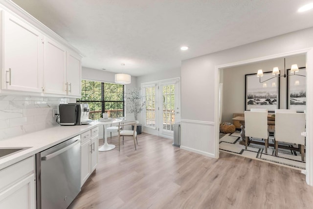 kitchen featuring white cabinets, tasteful backsplash, decorative light fixtures, dishwasher, and light hardwood / wood-style floors