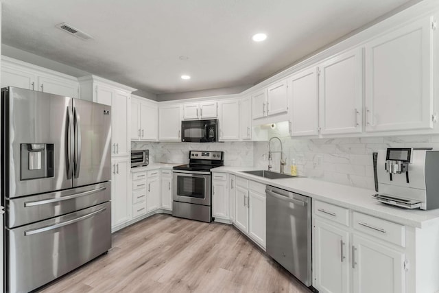 kitchen with tasteful backsplash, white cabinetry, sink, and appliances with stainless steel finishes