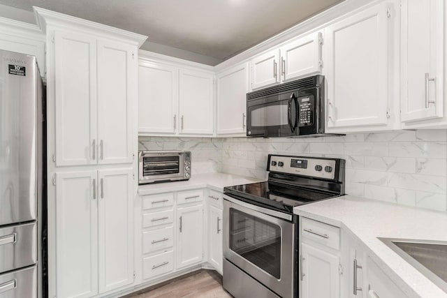 kitchen with white cabinets, backsplash, stainless steel appliances, and light hardwood / wood-style floors