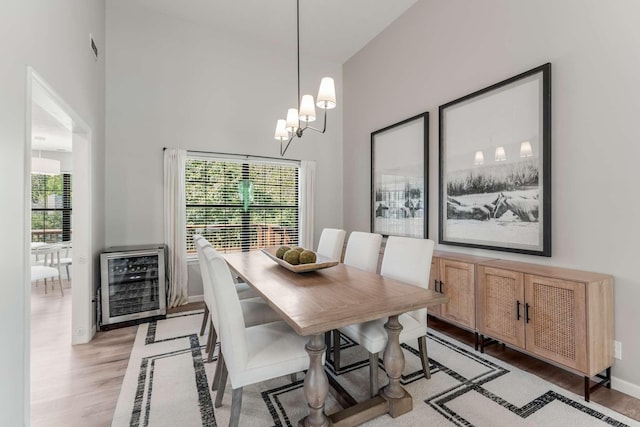 dining room with heating unit, a notable chandelier, a high ceiling, and light hardwood / wood-style flooring