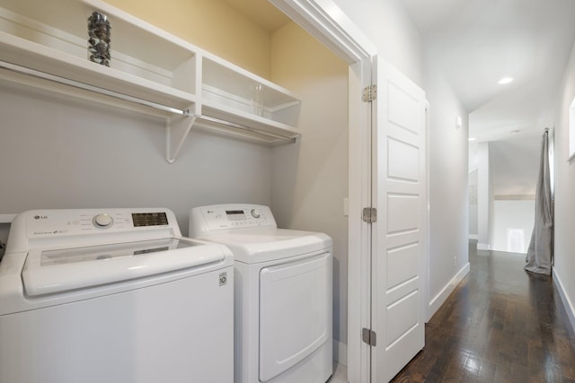 clothes washing area with washing machine and dryer and dark hardwood / wood-style flooring