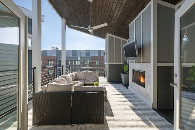 balcony with an outdoor living space with a fireplace and ceiling fan