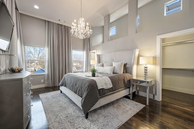 bedroom with dark wood-style flooring, a towering ceiling, baseboards, and an inviting chandelier