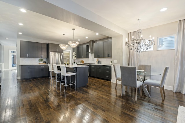 kitchen with a kitchen breakfast bar, decorative light fixtures, tasteful backsplash, and wall chimney exhaust hood