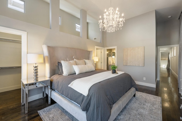 bedroom with dark hardwood / wood-style flooring, a high ceiling, and an inviting chandelier