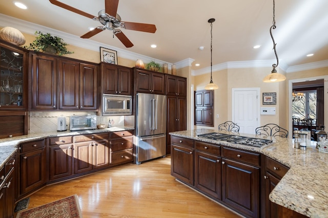 kitchen featuring stainless steel appliances, light stone countertops, dark brown cabinets, and pendant lighting