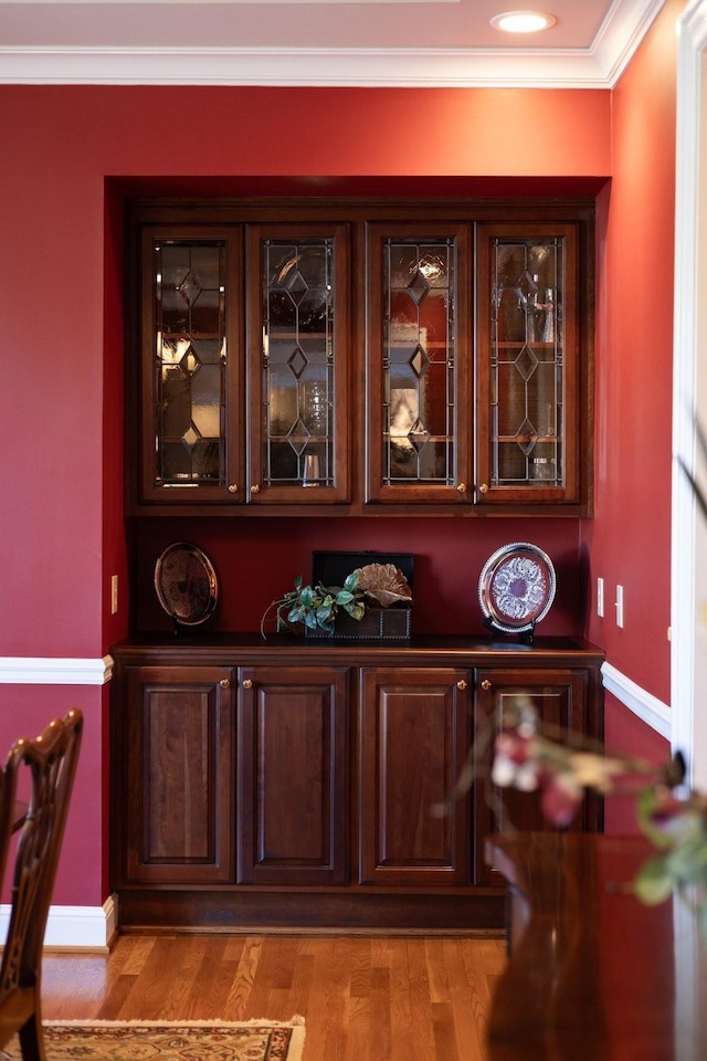 interior space with ornamental molding, dark brown cabinets, and light hardwood / wood-style floors