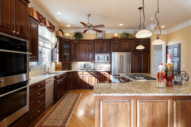 kitchen featuring tasteful backsplash, sink, hanging light fixtures, light stone counters, and stainless steel appliances