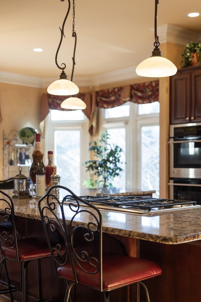 kitchen featuring stainless steel appliances, crown molding, decorative light fixtures, and dark stone counters