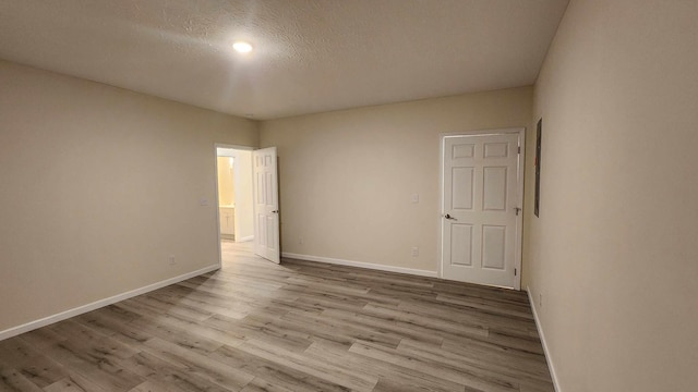 spare room with a textured ceiling and light hardwood / wood-style flooring