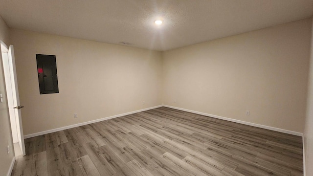 spare room with hardwood / wood-style floors, electric panel, and a textured ceiling