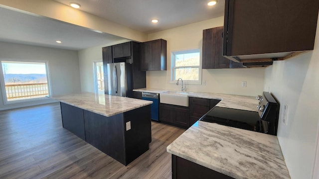 kitchen featuring light wood-type flooring, appliances with stainless steel finishes, sink, and a center island