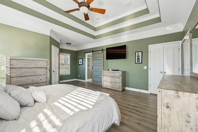 bedroom featuring ceiling fan, a barn door, crown molding, and a raised ceiling