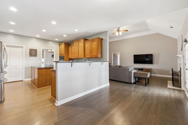 kitchen featuring dark wood-type flooring, a kitchen breakfast bar, a center island, and ceiling fan