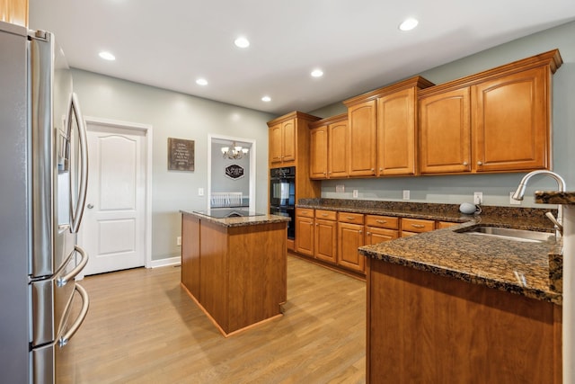 kitchen with sink, stainless steel fridge, dark stone counters, and a center island