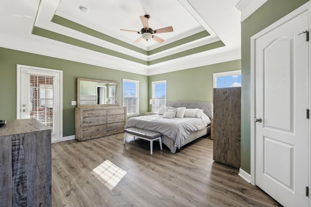 bedroom with hardwood / wood-style floors, ceiling fan, a raised ceiling, access to exterior, and crown molding