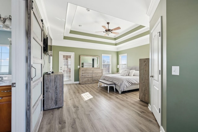 bedroom with ceiling fan, light hardwood / wood-style floors, ornamental molding, and a raised ceiling