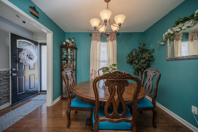 dining room featuring a textured ceiling, a chandelier, and dark hardwood / wood-style floors