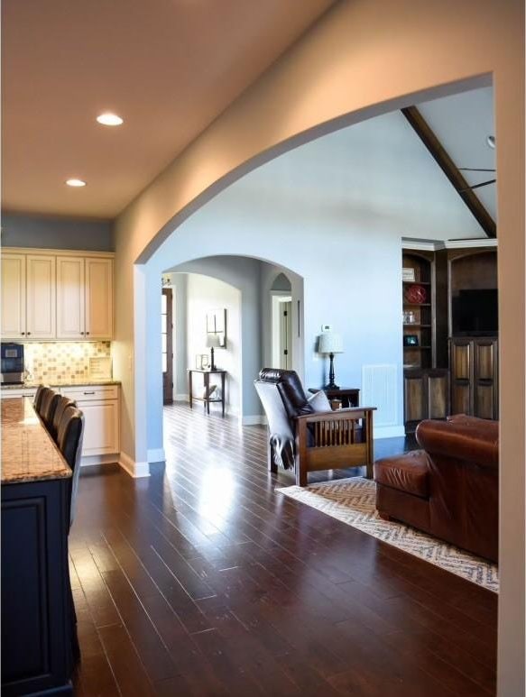 interior space with backsplash, cream cabinets, light stone countertops, and dark hardwood / wood-style floors