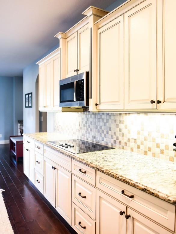 kitchen with cream cabinets, light stone counters, backsplash, and black electric cooktop