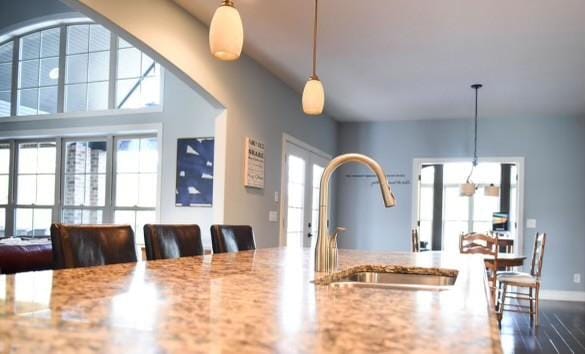 kitchen featuring light stone countertops, sink, and pendant lighting