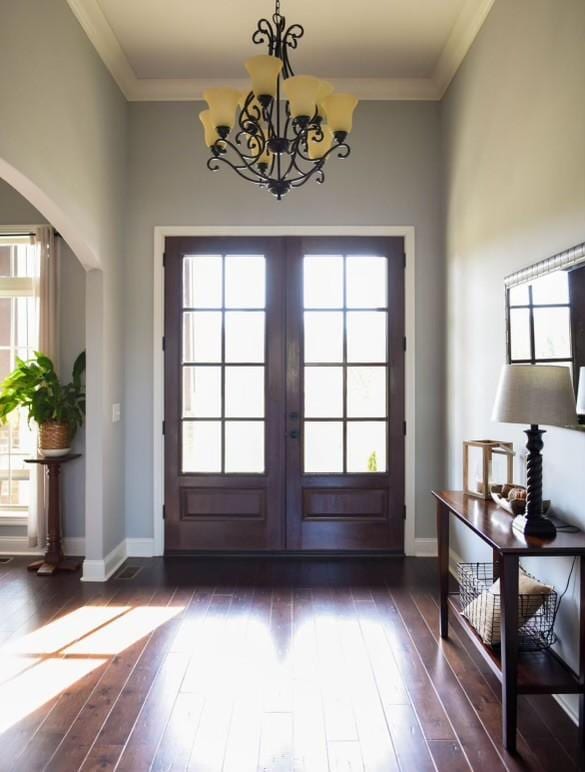 entryway with french doors, dark hardwood / wood-style floors, crown molding, and an inviting chandelier