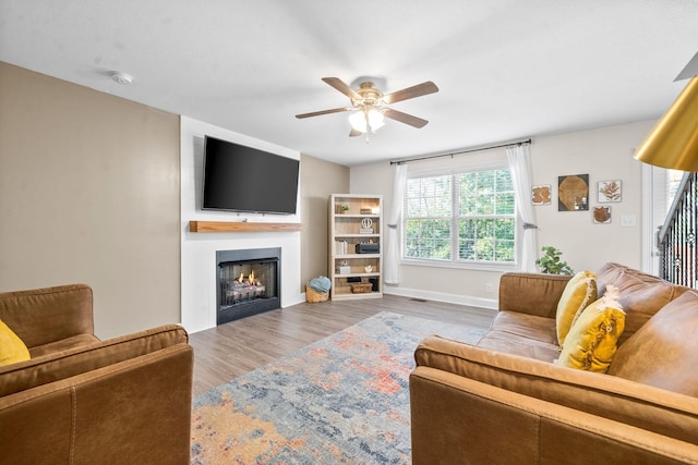 living room with ceiling fan, a large fireplace, and hardwood / wood-style floors