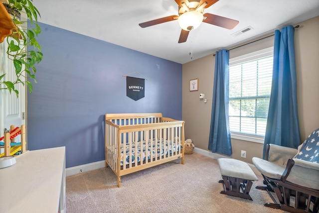 bedroom with carpet, ceiling fan, multiple windows, and a nursery area