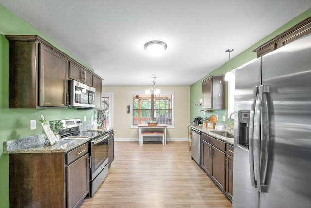 kitchen featuring dark brown cabinets, sink, decorative light fixtures, and appliances with stainless steel finishes